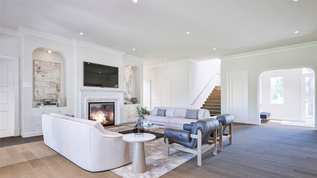 living room featuring a high end fireplace, crown molding, and hardwood / wood-style flooring