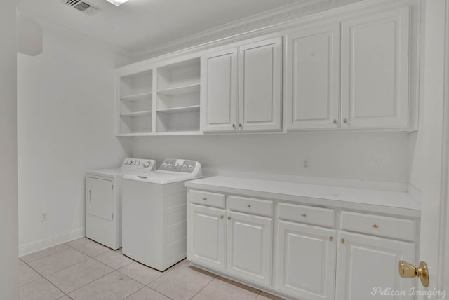 clothes washing area with ornamental molding, light tile patterned flooring, separate washer and dryer, and cabinets