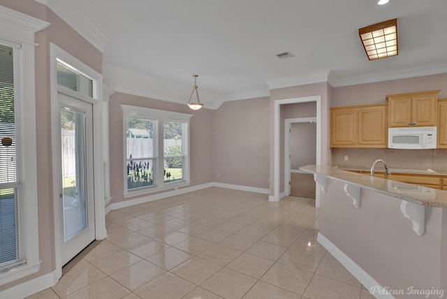 kitchen with light brown cabinets, a breakfast bar, crown molding, and a wealth of natural light