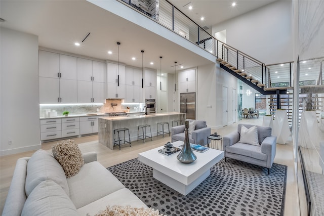 living room with sink, a towering ceiling, and light hardwood / wood-style flooring