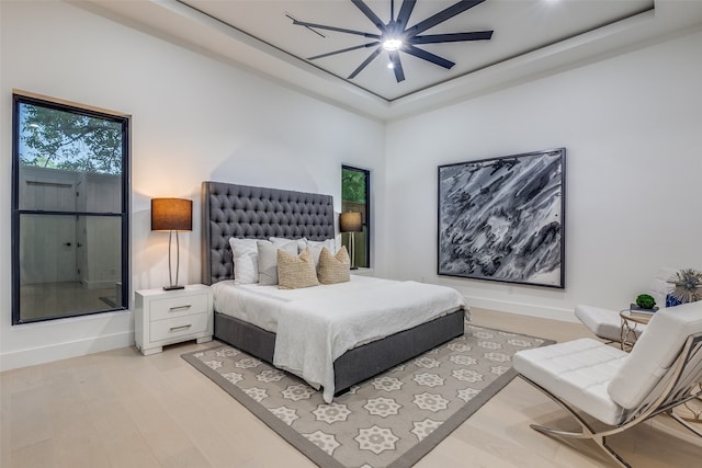 bedroom featuring ceiling fan, a tray ceiling, and light hardwood / wood-style floors