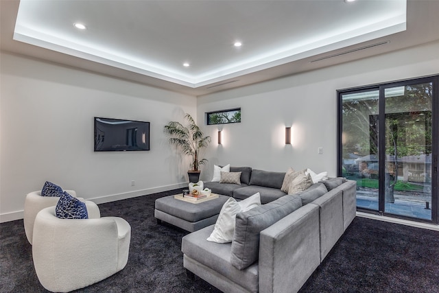 living room featuring dark colored carpet and a tray ceiling