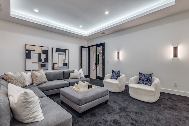 living room featuring a tray ceiling and dark colored carpet