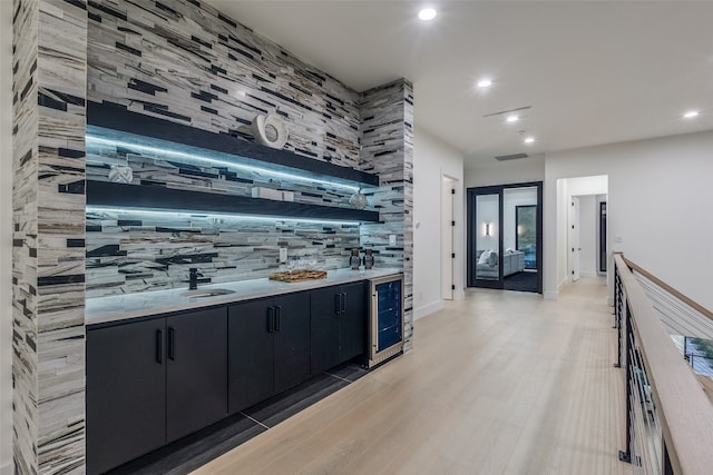 bar featuring tasteful backsplash, wine cooler, and light hardwood / wood-style flooring