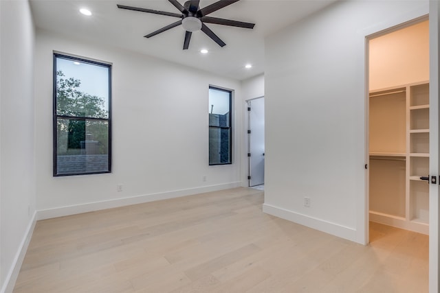 unfurnished bedroom featuring light wood-type flooring, ceiling fan, a closet, and a walk in closet