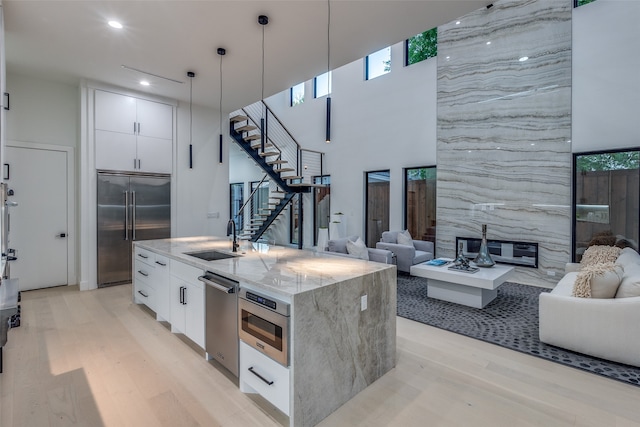 kitchen featuring pendant lighting, sink, white cabinetry, stainless steel appliances, and a high ceiling