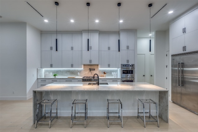 kitchen featuring pendant lighting, a kitchen island with sink, sink, and stainless steel appliances