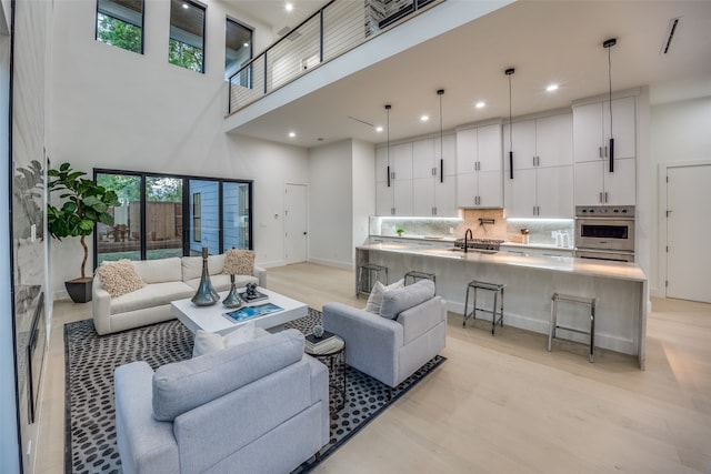 living room featuring light hardwood / wood-style floors, a towering ceiling, and sink