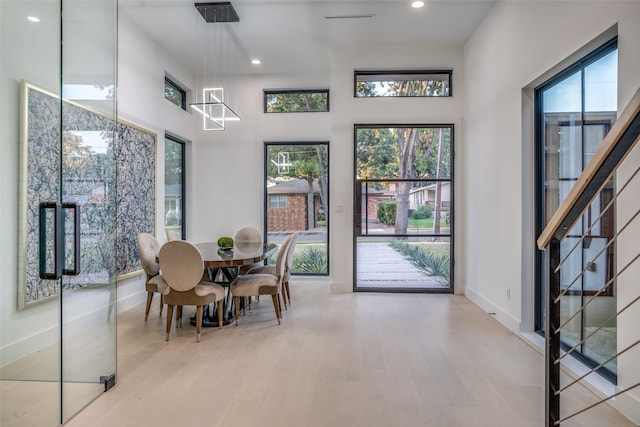 dining room with plenty of natural light, light hardwood / wood-style floors, and a high ceiling