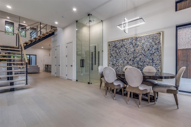 dining area with hardwood / wood-style floors, a towering ceiling, and an inviting chandelier