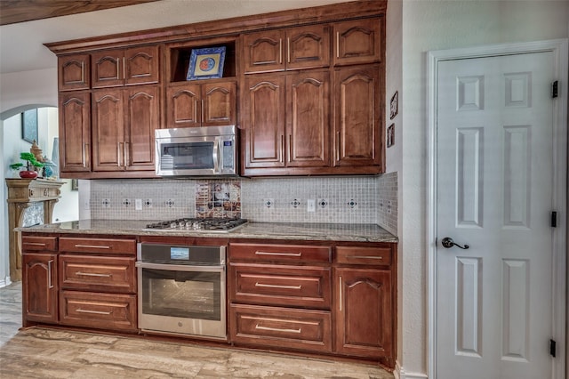 232 Touchdown Dr, Irving, TX 75063 - kitchen with stainless steel appliances, tasteful backsplash, stone countertops, and arched walkways
