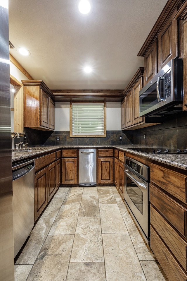 kitchen with dark stone counters, sink, decorative backsplash, and appliances with stainless steel finishes