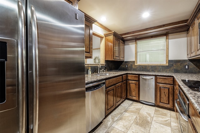 kitchen featuring stainless steel appliances, dark stone counters, sink, and tasteful backsplash