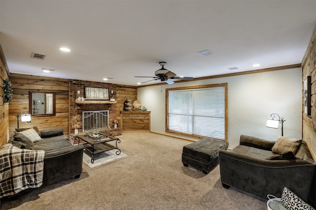 carpeted living room with wooden walls, crown molding, ceiling fan, and a fireplace