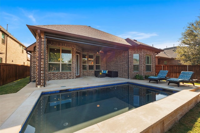 rear view of property with a fenced in pool and a patio area