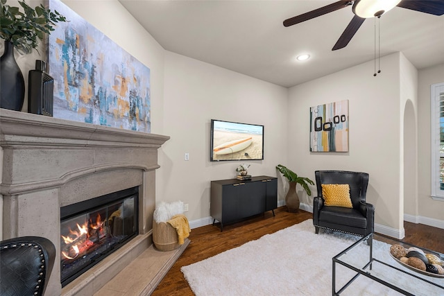 living area with dark wood-type flooring and ceiling fan