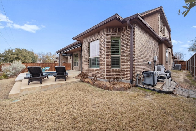 rear view of property featuring central AC, a patio area, and a lawn