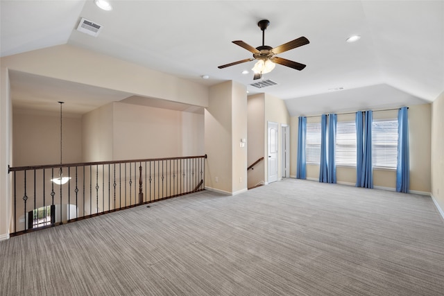 spare room with ceiling fan, vaulted ceiling, and light carpet