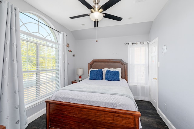 bedroom featuring lofted ceiling, dark hardwood / wood-style flooring, multiple windows, and ceiling fan