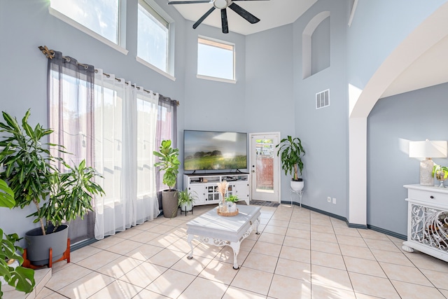 living room featuring ceiling fan, light tile patterned floors, and a high ceiling