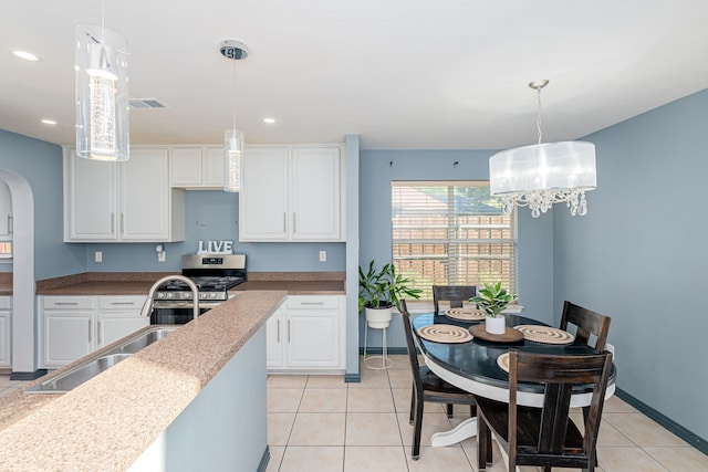 kitchen with white cabinets, decorative light fixtures, sink, and stainless steel range oven