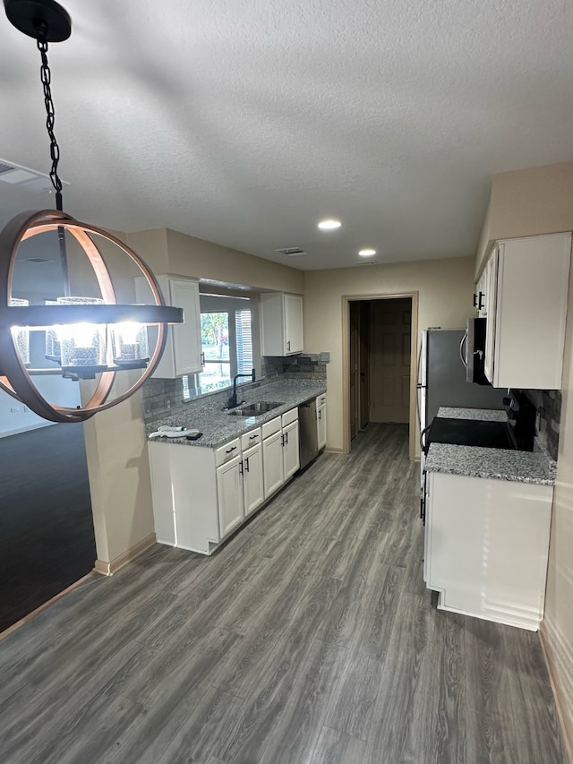 kitchen featuring stainless steel dishwasher, dark hardwood / wood-style floors, dark stone countertops, sink, and white cabinetry