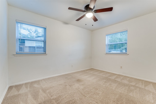 carpeted spare room featuring ceiling fan and a wealth of natural light