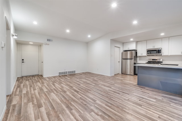 kitchen with appliances with stainless steel finishes, decorative backsplash, light hardwood / wood-style floors, and white cabinets