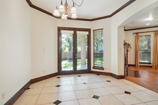 entryway with ornamental molding, french doors, a chandelier, and light wood-type flooring