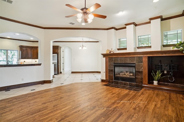 unfurnished living room featuring ceiling fan, crown molding, light wood-type flooring, and a fireplace