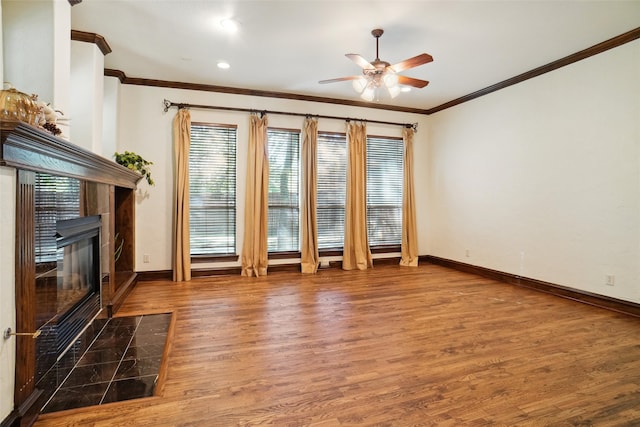 unfurnished living room with ceiling fan, a healthy amount of sunlight, wood-type flooring, and a tile fireplace