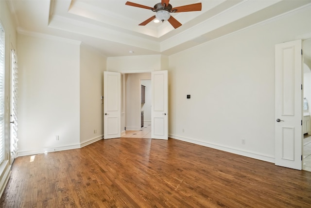 unfurnished bedroom with ceiling fan, wood-type flooring, ornamental molding, and a tray ceiling