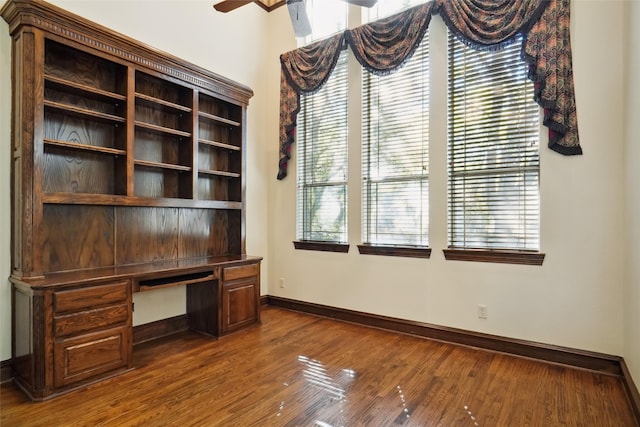 unfurnished office with a healthy amount of sunlight, wood-type flooring, and built in desk