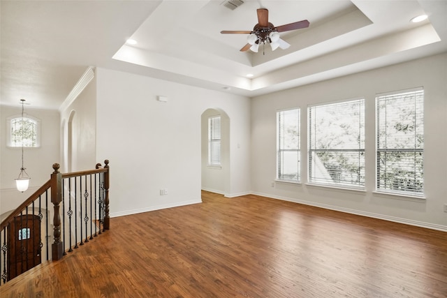 empty room with hardwood / wood-style floors, ceiling fan with notable chandelier, and a raised ceiling