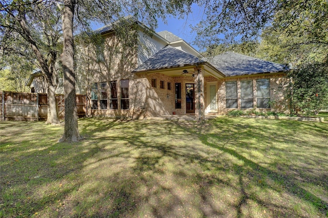 rear view of house featuring a yard and ceiling fan