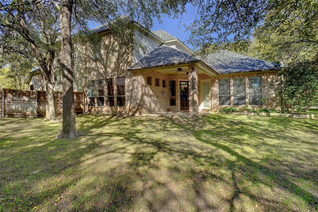 rear view of house featuring a yard and ceiling fan