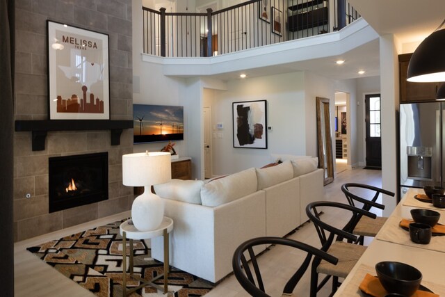 living room featuring a tiled fireplace and a towering ceiling