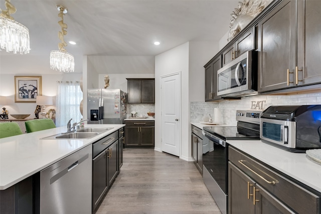 kitchen with sink, decorative light fixtures, stainless steel appliances, light hardwood / wood-style floors, and decorative backsplash