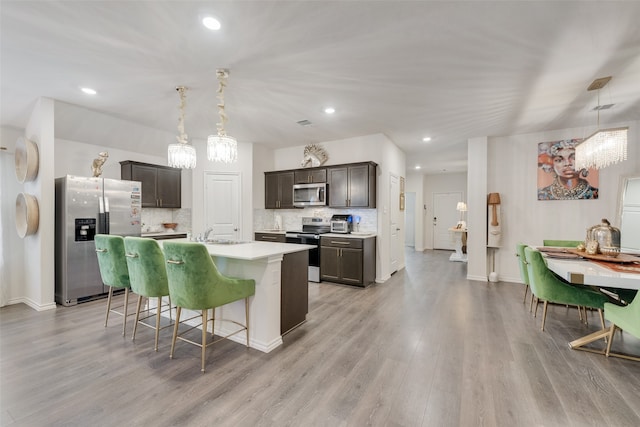 kitchen with decorative light fixtures, stainless steel appliances, light wood-type flooring, and a center island