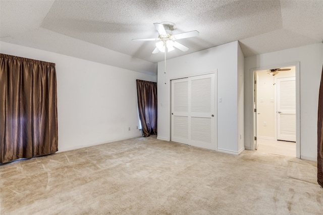 unfurnished bedroom featuring a closet, a textured ceiling, light carpet, and ceiling fan