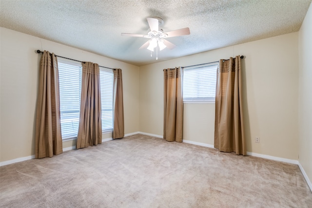 spare room with ceiling fan, plenty of natural light, and light carpet