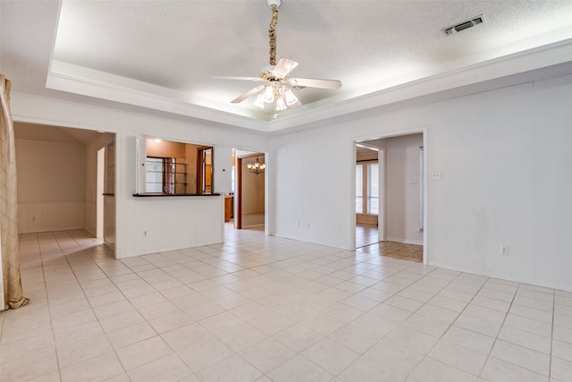 spare room featuring ceiling fan with notable chandelier, a textured ceiling, light tile patterned floors, and a raised ceiling