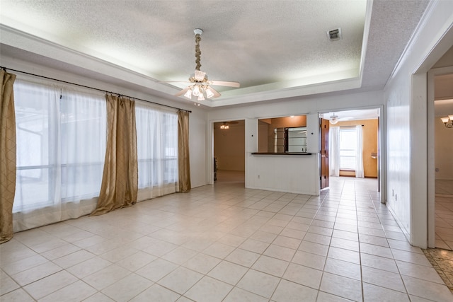 unfurnished living room featuring a textured ceiling, ceiling fan, a tray ceiling, and light tile patterned flooring