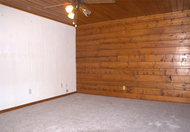 carpeted empty room featuring ceiling fan, wooden walls, and wood ceiling