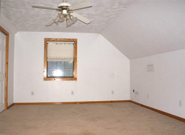 additional living space featuring lofted ceiling, ceiling fan, light colored carpet, and a textured ceiling