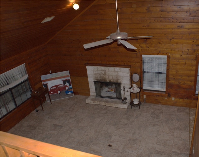 living room with a stone fireplace, wooden walls, lofted ceiling, ceiling fan, and wood ceiling