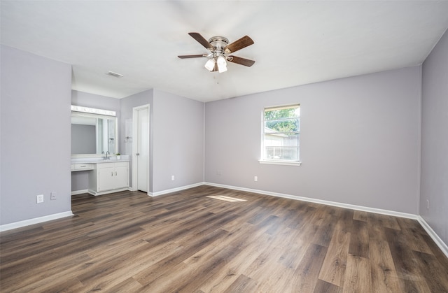 unfurnished bedroom featuring dark wood-type flooring, sink, ceiling fan, built in desk, and connected bathroom