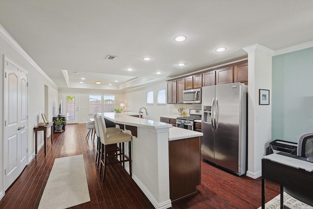 kitchen featuring stainless steel appliances, a breakfast bar area, a center island with sink, and dark hardwood / wood-style flooring