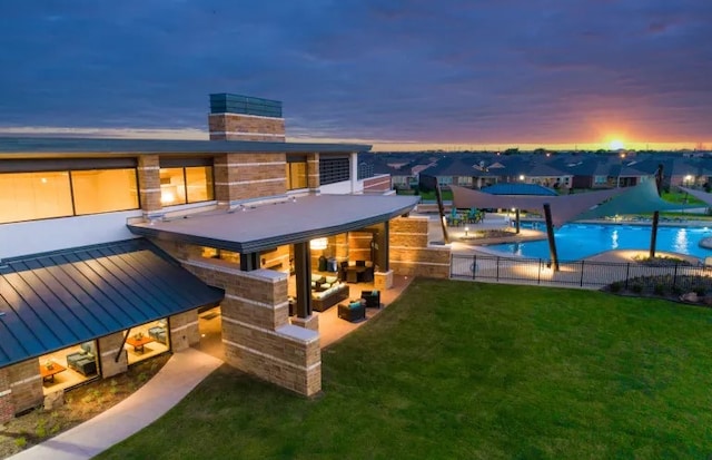 back house at dusk with a yard and a patio area