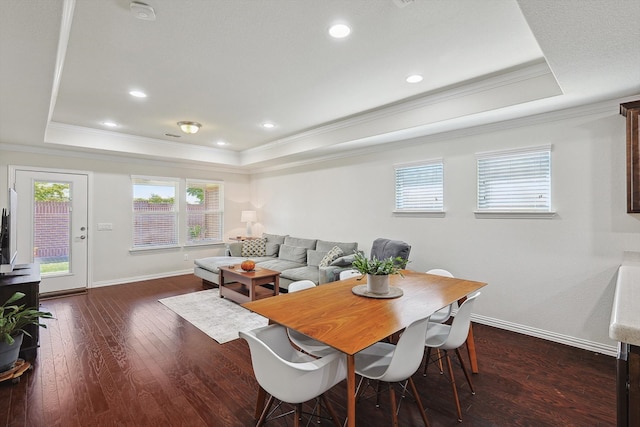 dining area featuring dark wood-type flooring, crown molding, and a tray ceiling